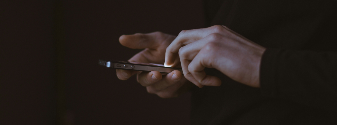 Close-up of a person using a smartphone in low light, illustrating mobile app interaction or engagement