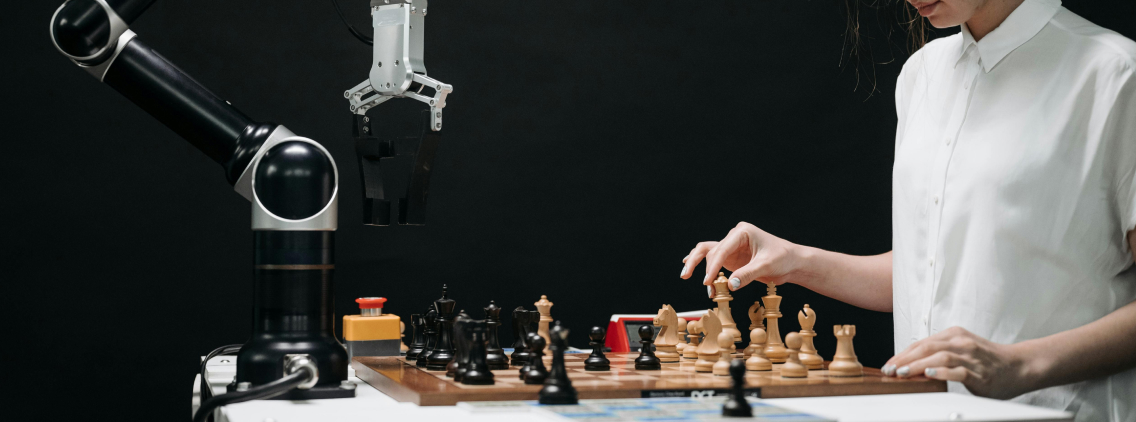 A woman playing chess against a robotic arm, symbolizing the interaction between human intelligence and machine learning in a controlled environment