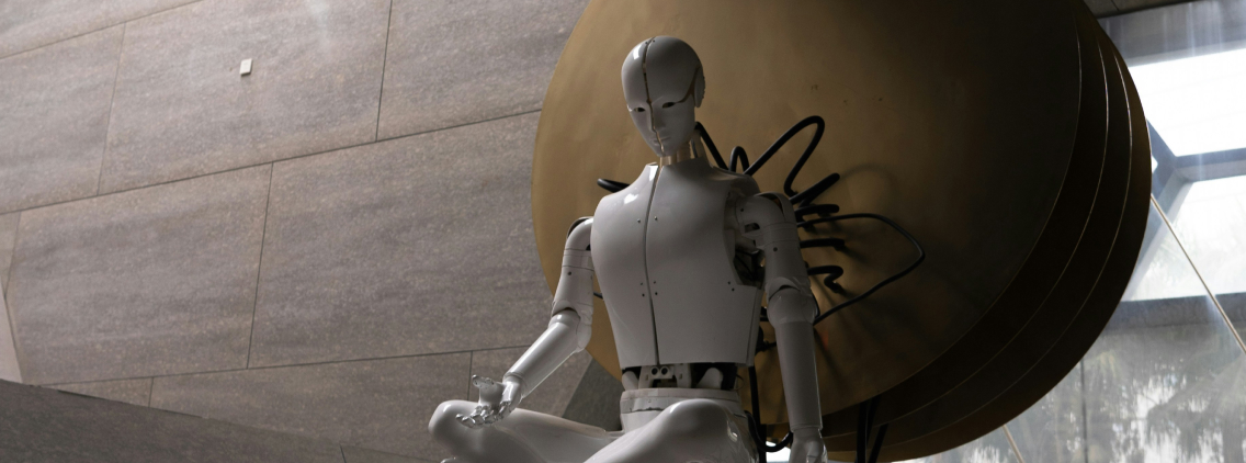 A humanoid robot in a meditative pose, seated in front of a large circular sculpture in a modern, minimalist interior space, symbolizing the intersection of artificial intelligence and mindfulness