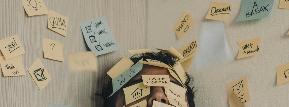 Person overwhelmed by sticky notes with reminders like 'Take a break', 'Calm', and 'Work out', symbolizing burnout and mental overload