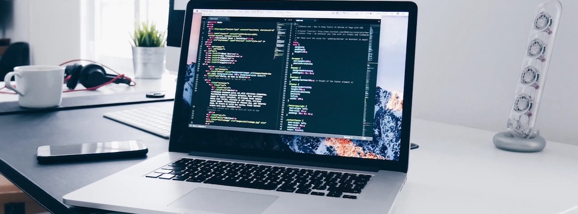 A laptop on a desk with two coding windows on it