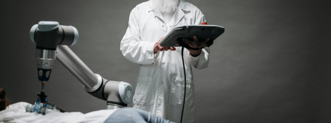 A healthcare professional operating a robotic arm using a digital control tablet, illustrating the integration of artificial intelligence and robotics in modern medical procedures.