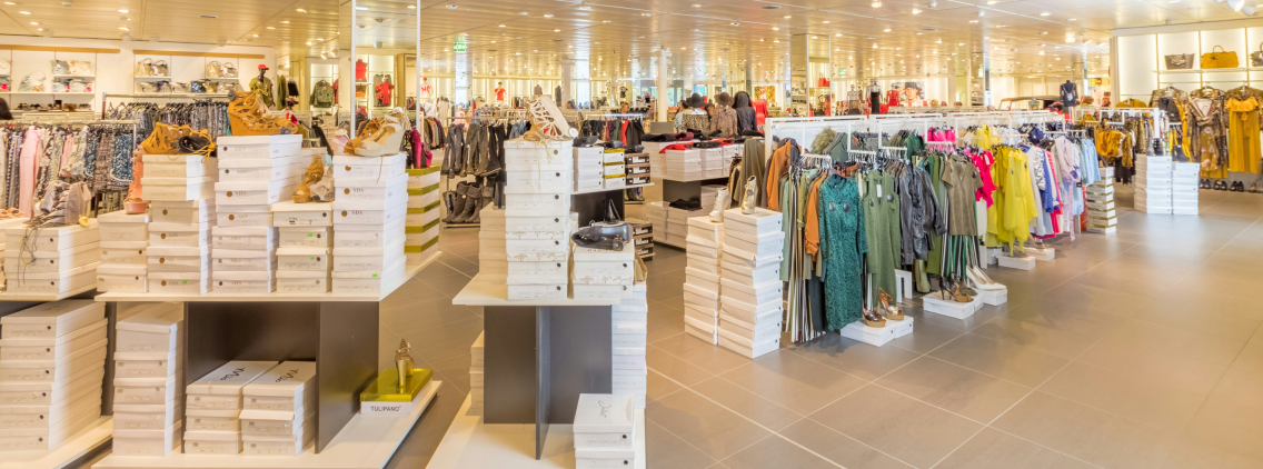 Bright and modern retail store interior displaying neatly arranged clothing racks and shoe boxes, representing organized inventory and merchandising strategies.